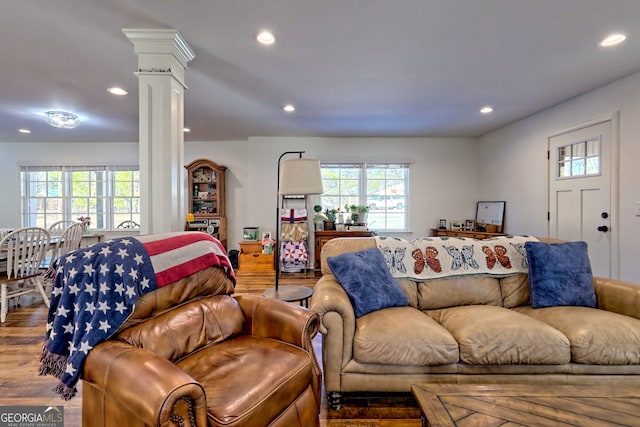 living room featuring decorative columns, plenty of natural light, and hardwood / wood-style flooring