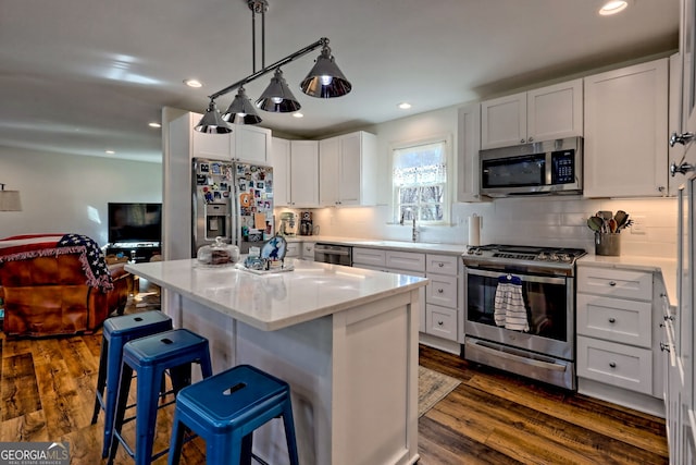 kitchen featuring stainless steel appliances, white cabinetry, a kitchen island, and dark wood-type flooring