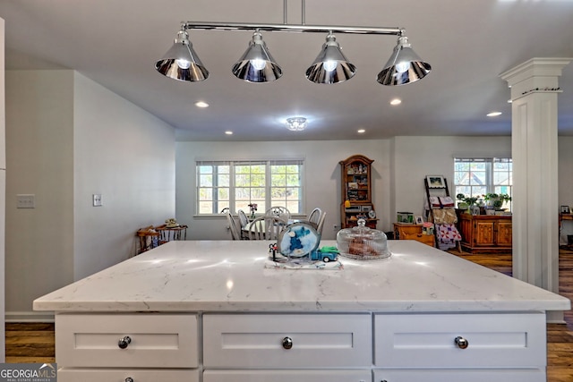 kitchen with white cabinets, light stone counters, decorative columns, and plenty of natural light