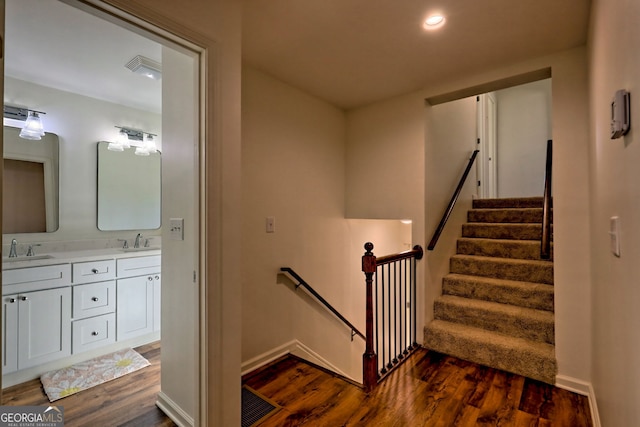 stairs featuring sink and hardwood / wood-style flooring