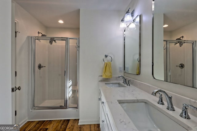 bathroom with wood-type flooring, vanity, and a shower with door