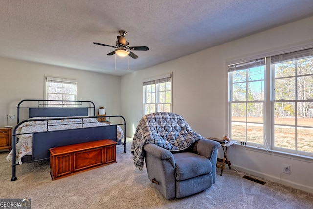 carpeted bedroom featuring ceiling fan and a textured ceiling