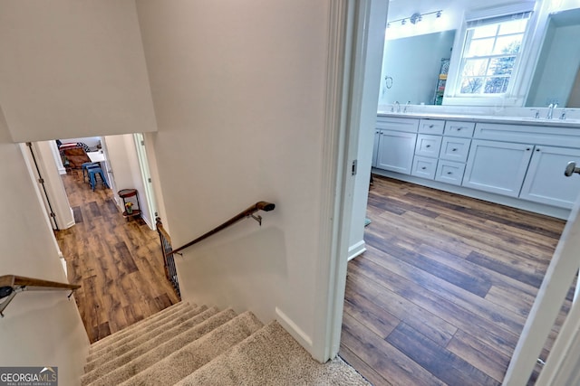 staircase featuring hardwood / wood-style flooring and sink