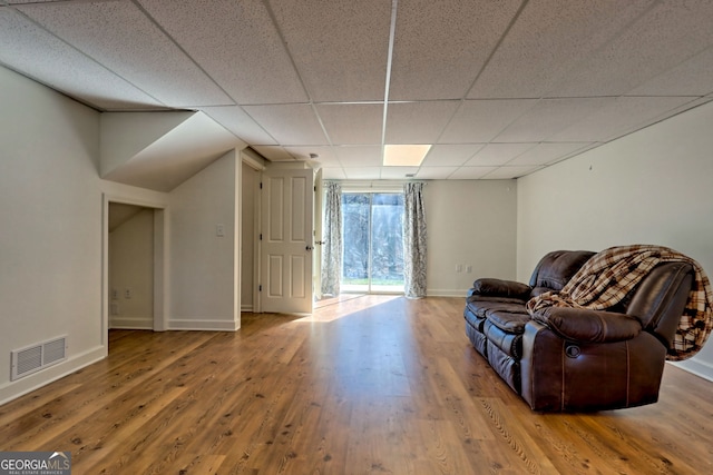 living area with a paneled ceiling and hardwood / wood-style flooring