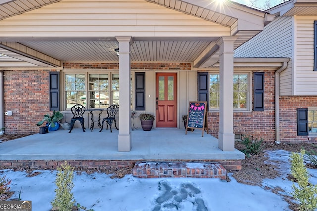 snow covered property entrance with a porch