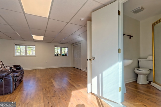 sitting room featuring a drop ceiling and light wood-type flooring