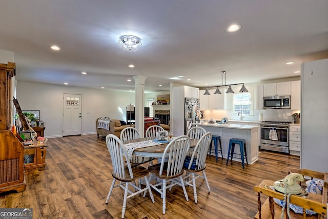 dining space featuring decorative columns and hardwood / wood-style flooring