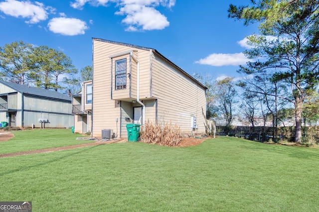 rear view of property featuring a yard and central air condition unit