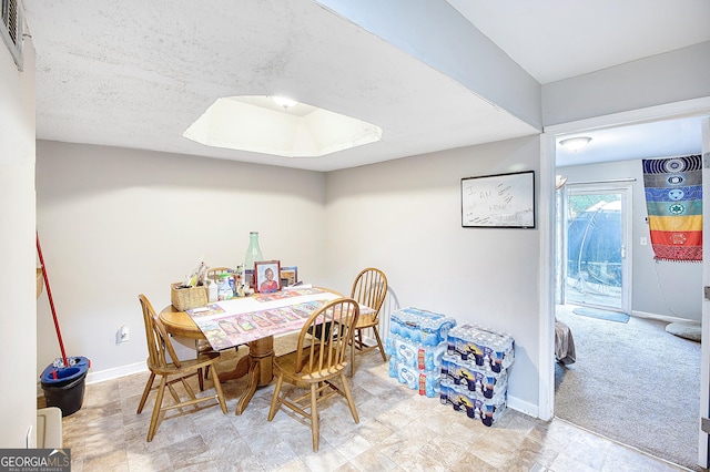 dining space with light colored carpet and a textured ceiling