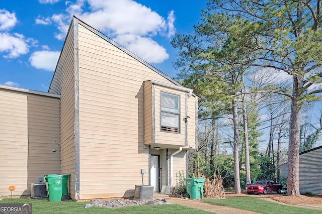 exterior space featuring central air condition unit and a lawn