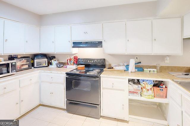 kitchen with white cabinets, light tile patterned flooring, and black electric range