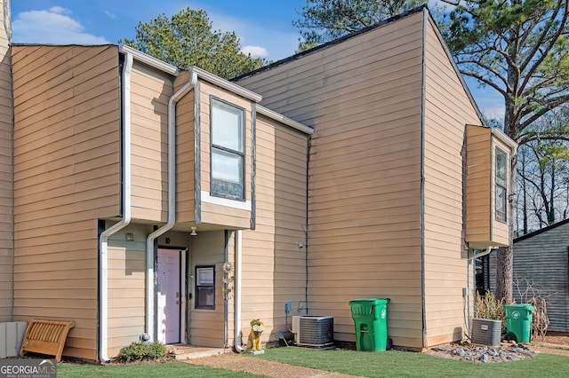 rear view of property featuring a yard and central AC unit