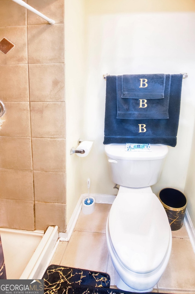 bathroom featuring toilet, tiled shower, and tile patterned floors