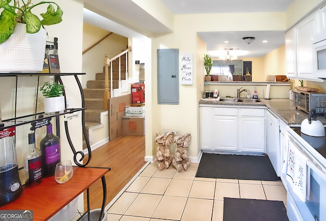 kitchen with electric panel, white cabinetry, sink, and light tile patterned floors