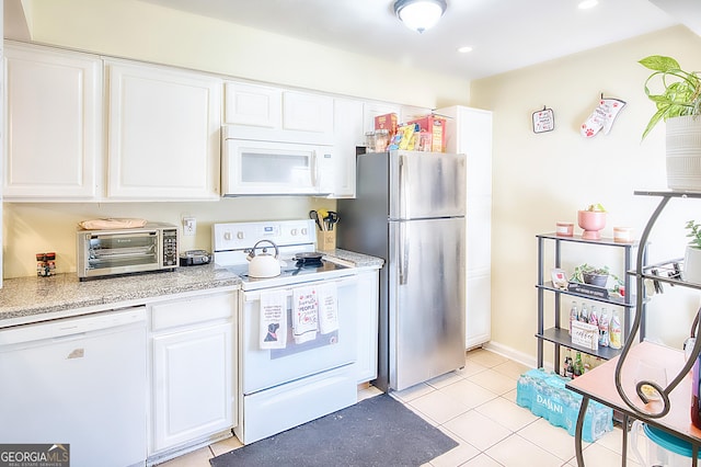 kitchen featuring white appliances, white cabinetry, light stone counters, and light tile patterned flooring