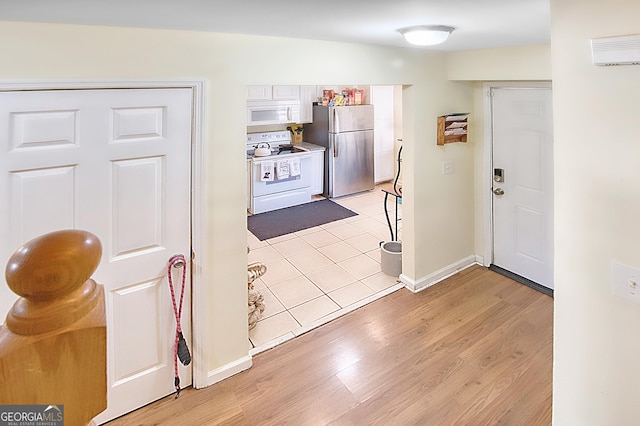 kitchen with white appliances, white cabinets, and light hardwood / wood-style floors