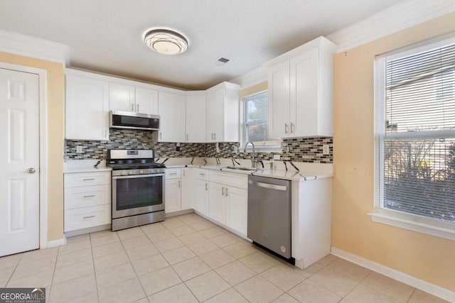 kitchen with sink, appliances with stainless steel finishes, light tile patterned floors, and white cabinetry