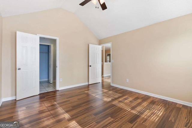 unfurnished bedroom with ceiling fan, dark hardwood / wood-style flooring, a spacious closet, and vaulted ceiling