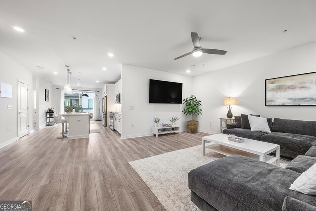 kitchen featuring stainless steel appliances, decorative light fixtures, a kitchen island with sink, white cabinets, and a breakfast bar