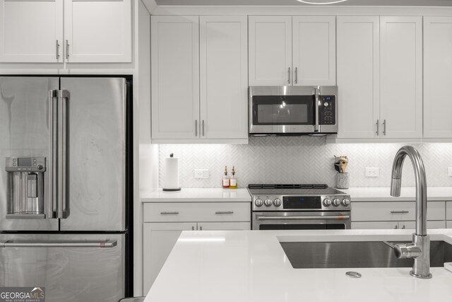 kitchen featuring stainless steel appliances, white cabinets, tasteful backsplash, and sink