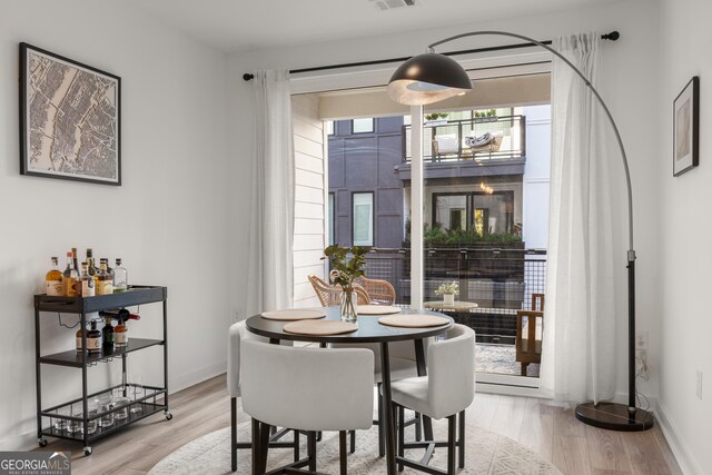 dining area with light hardwood / wood-style floors and indoor bar