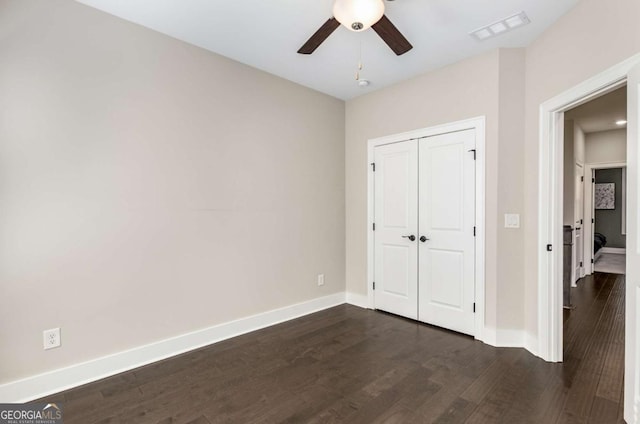 unfurnished bedroom with ceiling fan, dark hardwood / wood-style flooring, and a closet