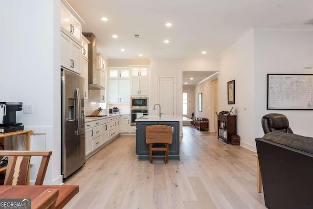 kitchen with a kitchen bar, a kitchen island with sink, white cabinetry, appliances with stainless steel finishes, and ornamental molding