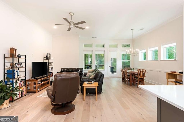 living room with ceiling fan with notable chandelier, light wood-type flooring, and crown molding