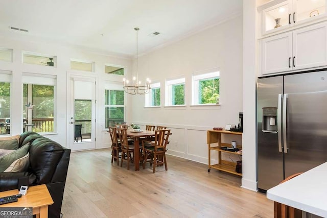 dining room with a notable chandelier, crown molding, and light hardwood / wood-style floors