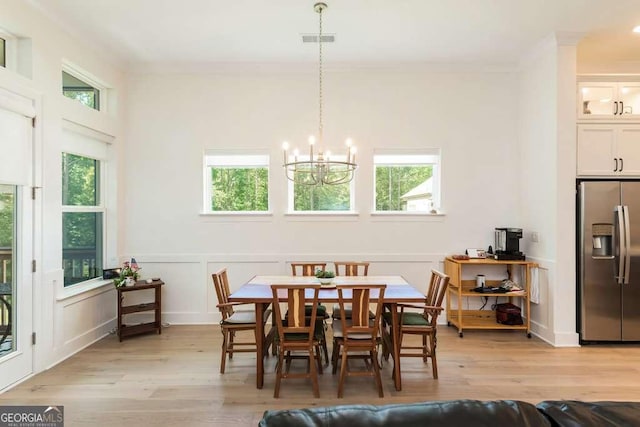 dining area featuring crown molding, light hardwood / wood-style floors, and a notable chandelier