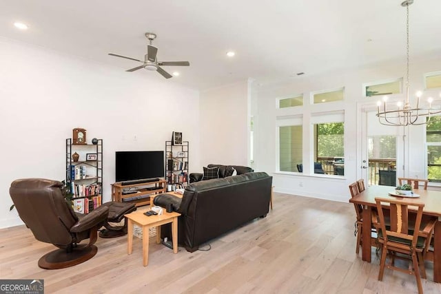 living room with ceiling fan with notable chandelier and light hardwood / wood-style flooring