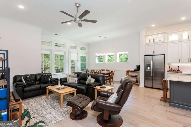 living room featuring ceiling fan with notable chandelier, light hardwood / wood-style floors, and crown molding