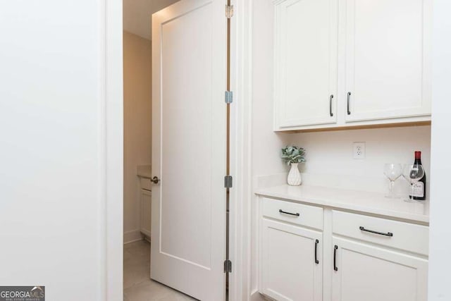 bar with white cabinets and light tile patterned floors