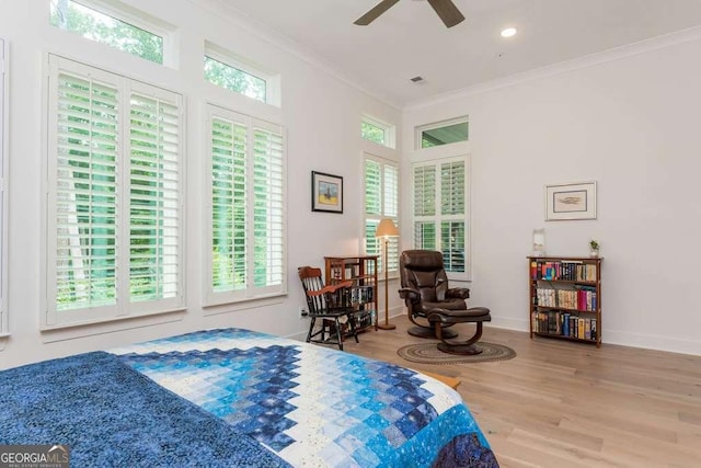 bedroom featuring wood-type flooring, multiple windows, ceiling fan, and ornamental molding