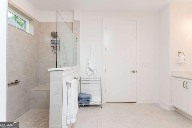 bathroom with a tile shower and vanity