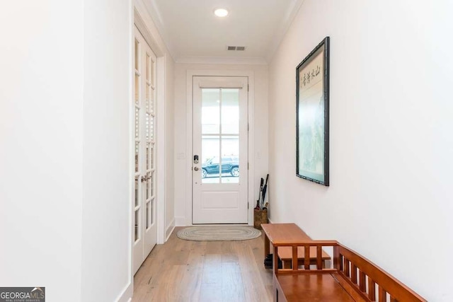 doorway with light wood-type flooring and crown molding