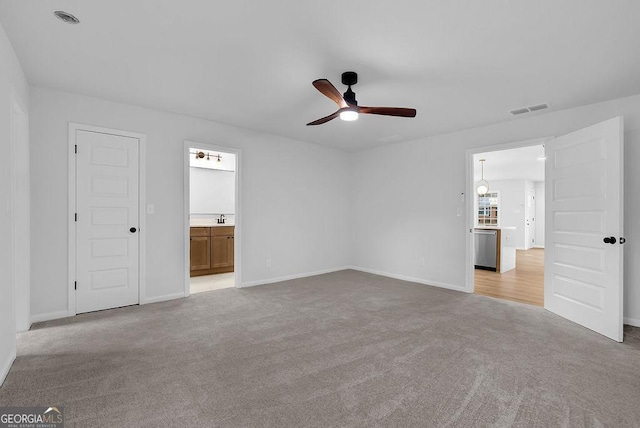 unfurnished bedroom featuring ensuite bath, visible vents, baseboards, and light colored carpet