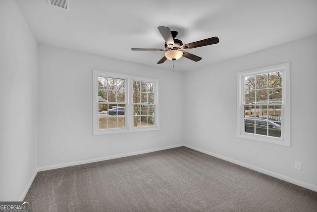 carpeted empty room with visible vents, baseboards, and a ceiling fan