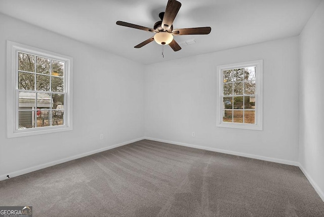 carpeted empty room featuring ceiling fan and baseboards