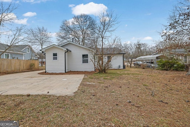 rear view of house featuring a yard and fence