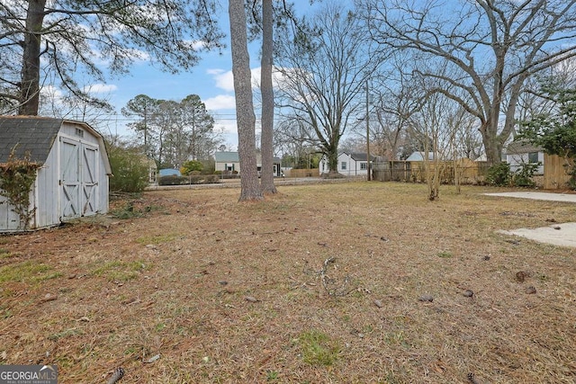 view of yard featuring an outbuilding, a storage unit, and fence