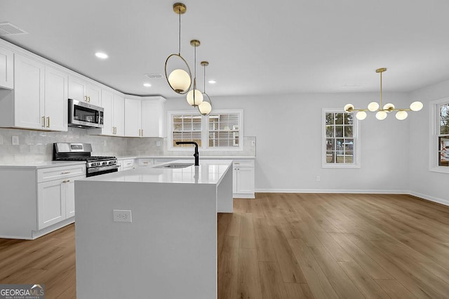 kitchen featuring appliances with stainless steel finishes, light countertops, a sink, and white cabinetry