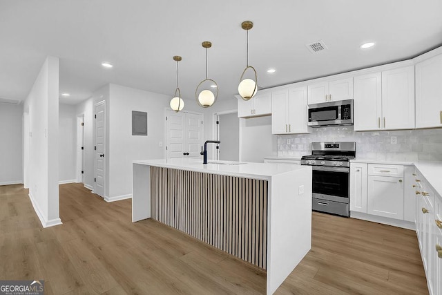 kitchen with a center island with sink, light countertops, appliances with stainless steel finishes, white cabinetry, and a sink