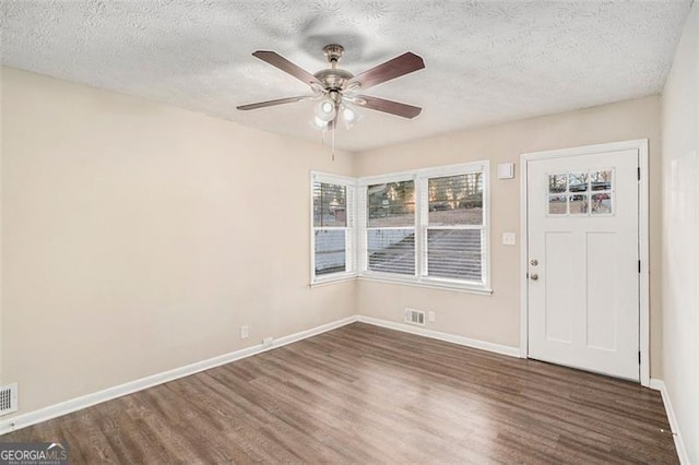 interior space featuring a textured ceiling, dark wood-type flooring, and ceiling fan