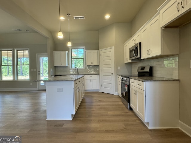 kitchen featuring pendant lighting, a kitchen island, white cabinets, appliances with stainless steel finishes, and dark stone countertops