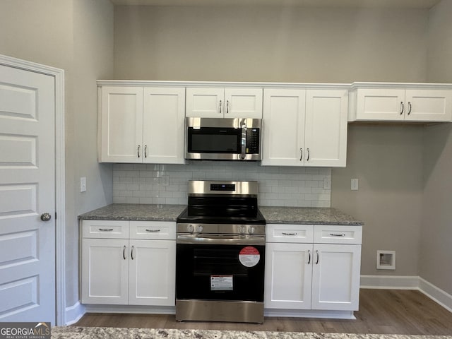 kitchen with light stone counters, stainless steel appliances, and white cabinets