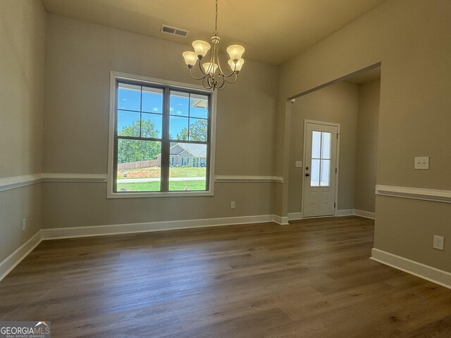 unfurnished dining area featuring dark wood-type flooring and an inviting chandelier