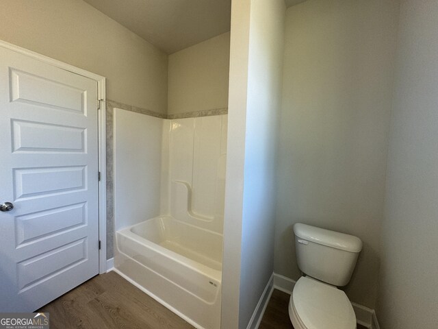 bathroom with toilet, washtub / shower combination, and wood-type flooring