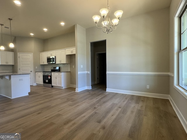 kitchen featuring tasteful backsplash, stainless steel appliances, hanging light fixtures, and white cabinetry