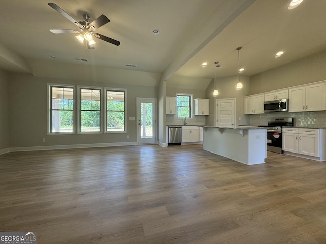 kitchen featuring white cabinets, a center island, backsplash, pendant lighting, and appliances with stainless steel finishes